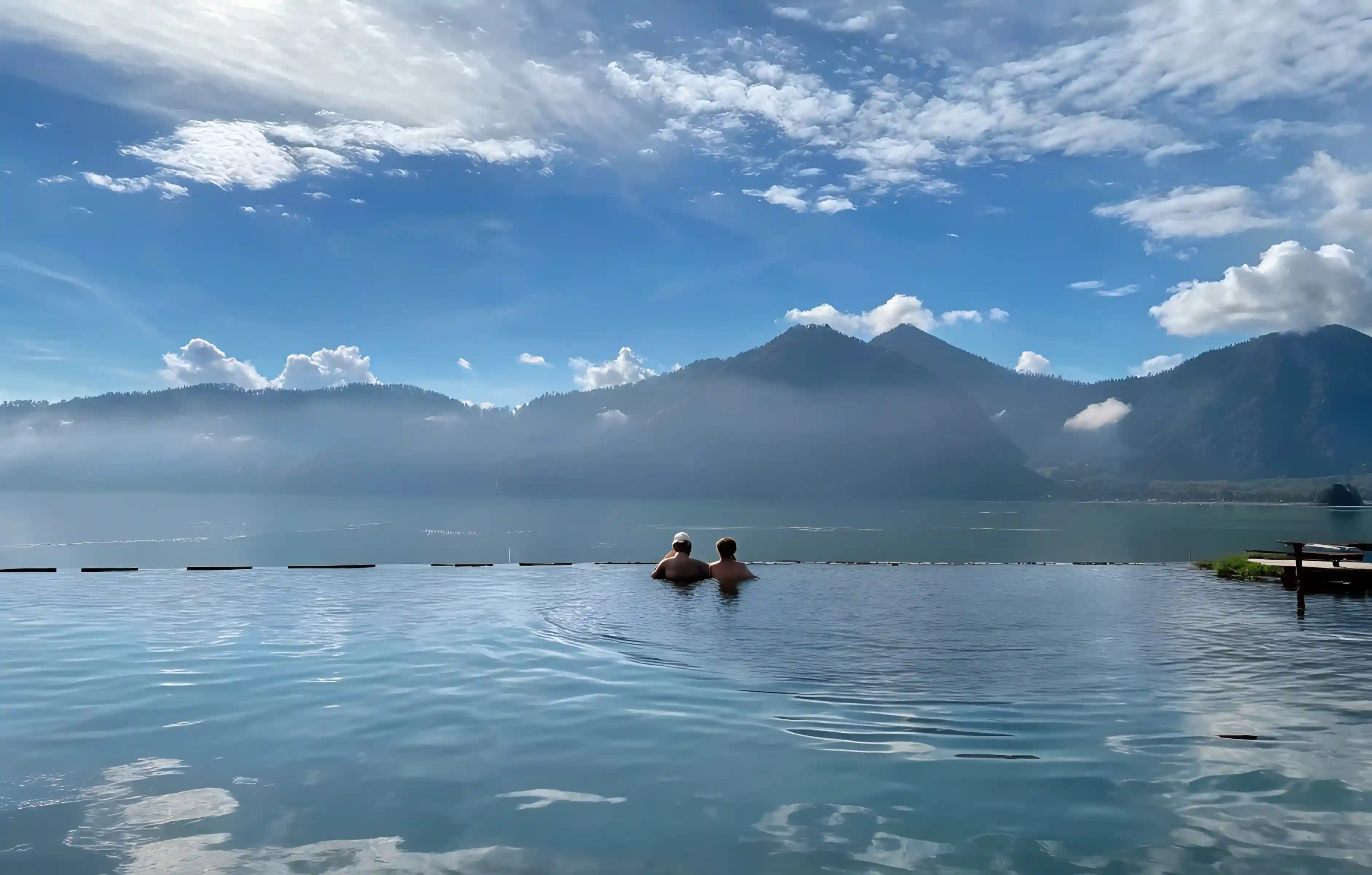 Couple in a natural hot spring pool facing Mount Batur and its lake, Bali