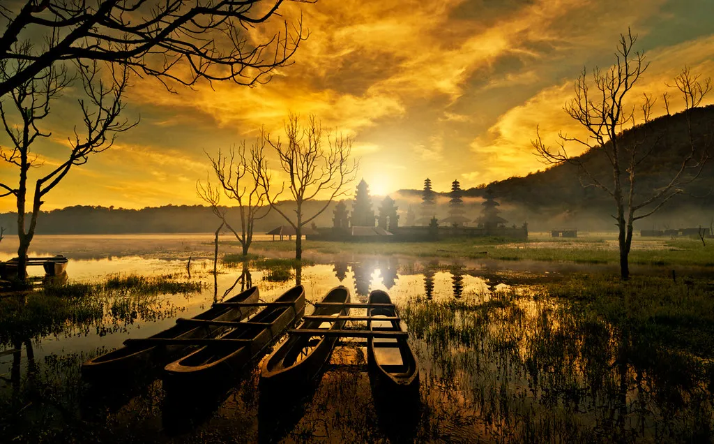 Sunrise over the lake temple and traditional canoes at Lake Tamblingan, Bali